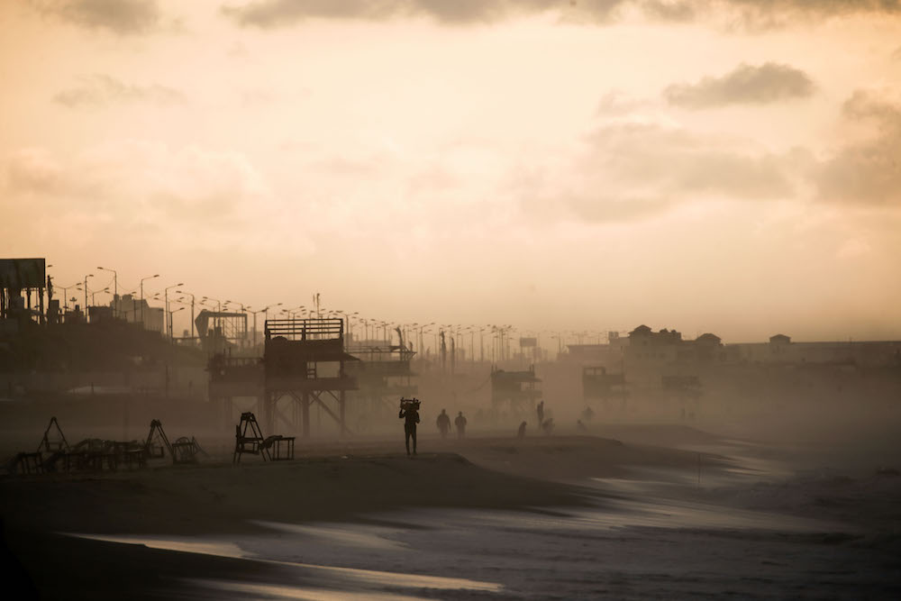 Palestinians brave the rainy weather for a walk on the beach before the nightly COVID-19 curfew begins in Gaza City, on January 19, 2021. (AFP/File Photo)