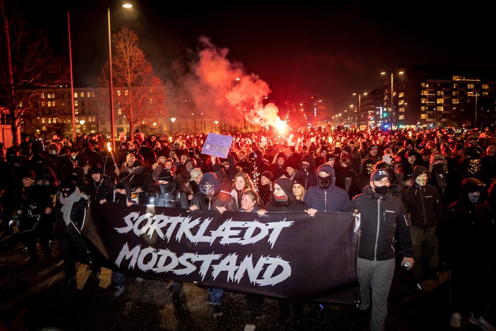 Demonstrators march with a banner reading 'Black-clad resistance' during a protest march organised by radical group 'Men in Black Denmark' against restrictions introduced by the Danish government during the novel coronavirus (Covid-19) pandemic, in Copenhagen on January 23, 2021. (AFP/File Photo)