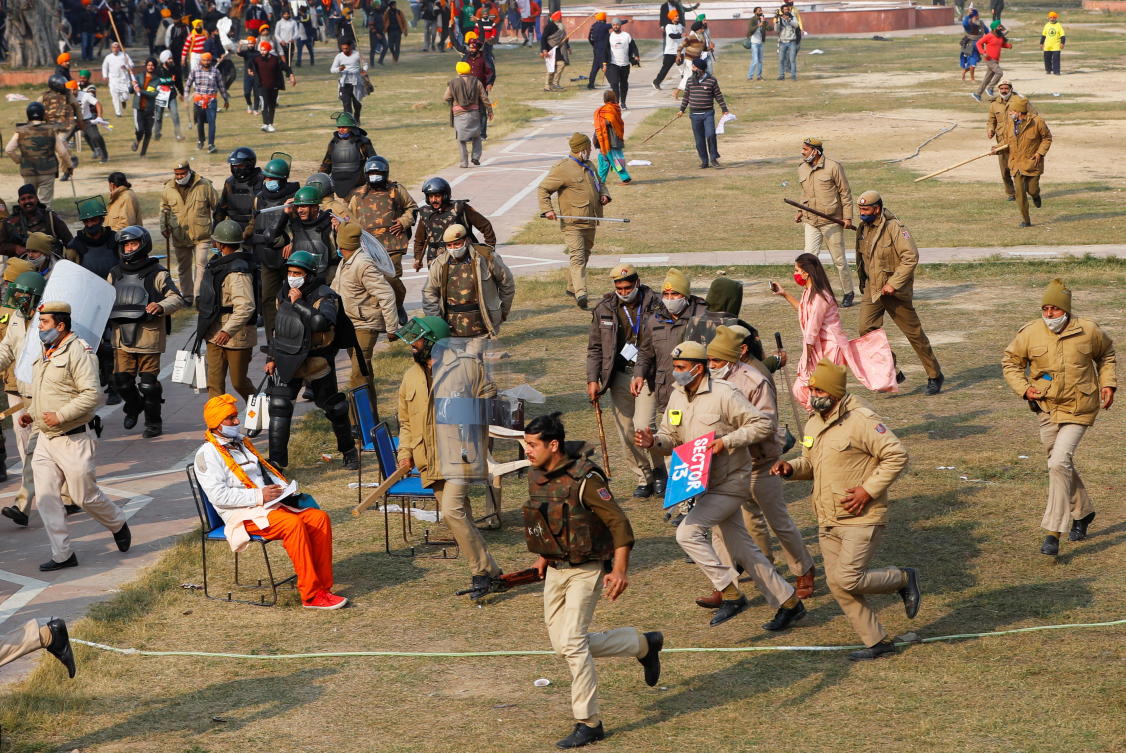 Police officers run during a protest of farmers against farm laws introduced by the government, at the historic Red Fort in Delhi, India, January 26, 2021. REUTERS/Adnan Abidi