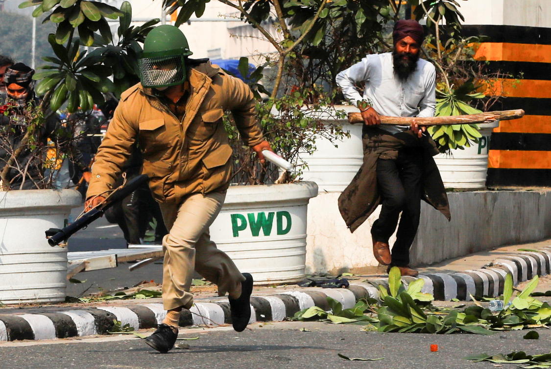 A farmer runs behind a police officer during a protest against farm laws introduced by the government, in New Delhi, India, January 26, 2021. REUTERS/Adnan Abidi