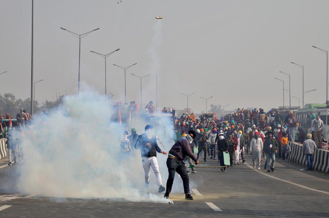 A man throws a tear gas canister back at police during a tractor rally held by farmers to protest farm laws on the occasion of India's Republic Day at Ghazipur border near Delhi, India, January 26, 2021. REUTERS/Stringer NO RESALES. NO ARCHIVES