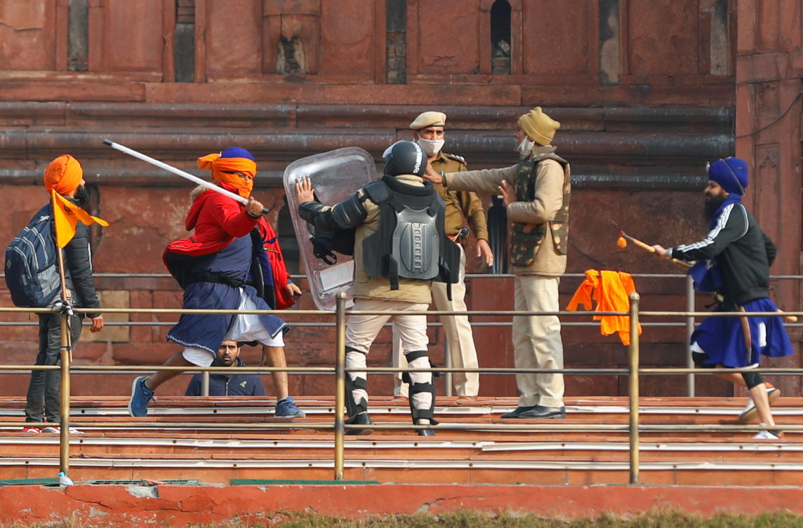 A Nihang (sikh warrior) beats a policeman with a baton during a protest against farm laws introduced by the government, at the historic Red Fort in Delhi, India, January 26, 2021. REUTERS/Adnan Abidi