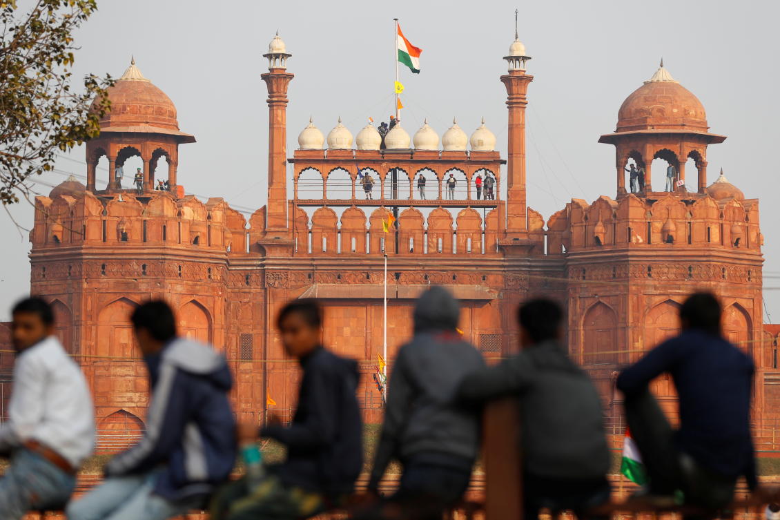A farmer holds a flag on top of the historic Red Fort, during a protest against farm laws introduced by the government, in Delhi, India, January 26, 2021. REUTERS/Adnan Abidi