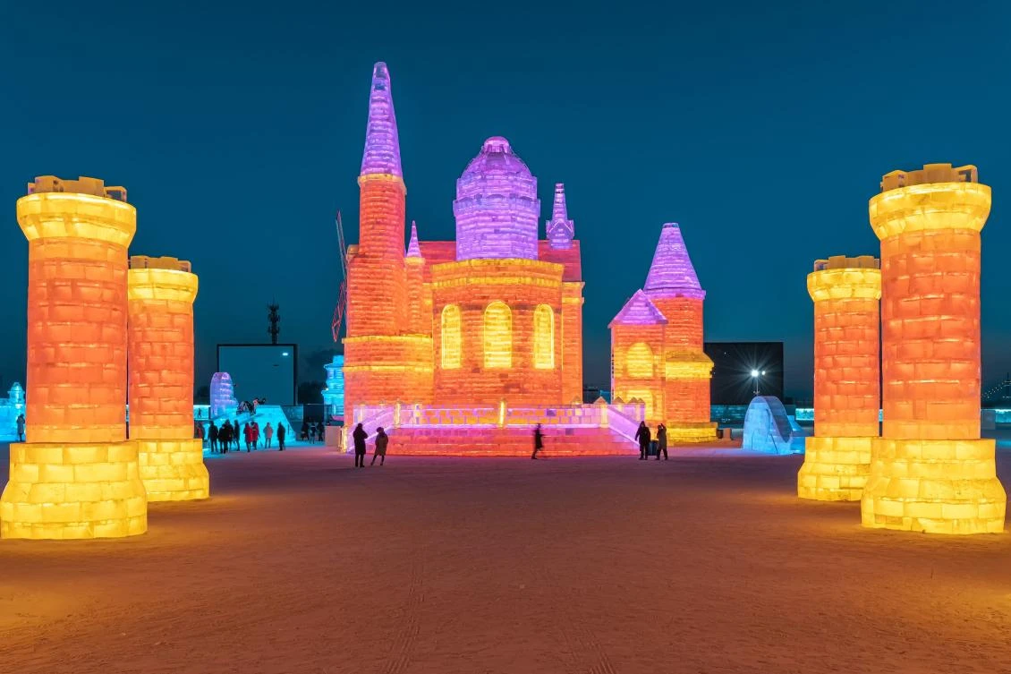 This photo taken on January 4, 2021 shows people looking at ice sculptures at the Harbin Ice and Snow Festival in Harbin, in northeastern China's Heilongjiang province. - China OUT / AFP / STR
