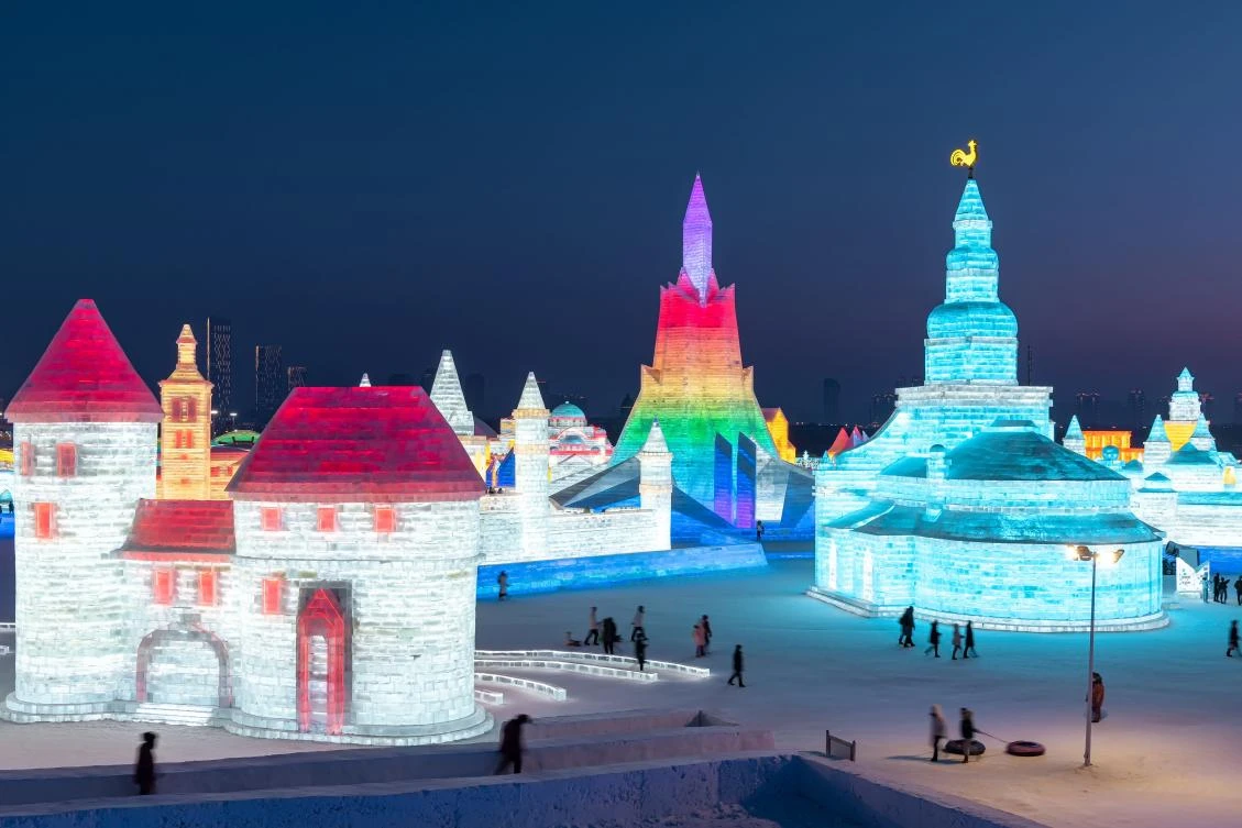 This photo taken on January 4, 2021 shows people looking at ice sculptures at the Harbin Ice and Snow Festival in Harbin, in northeastern China's Heilongjiang province on January 5, 2021. - China OUT / AFP / STR