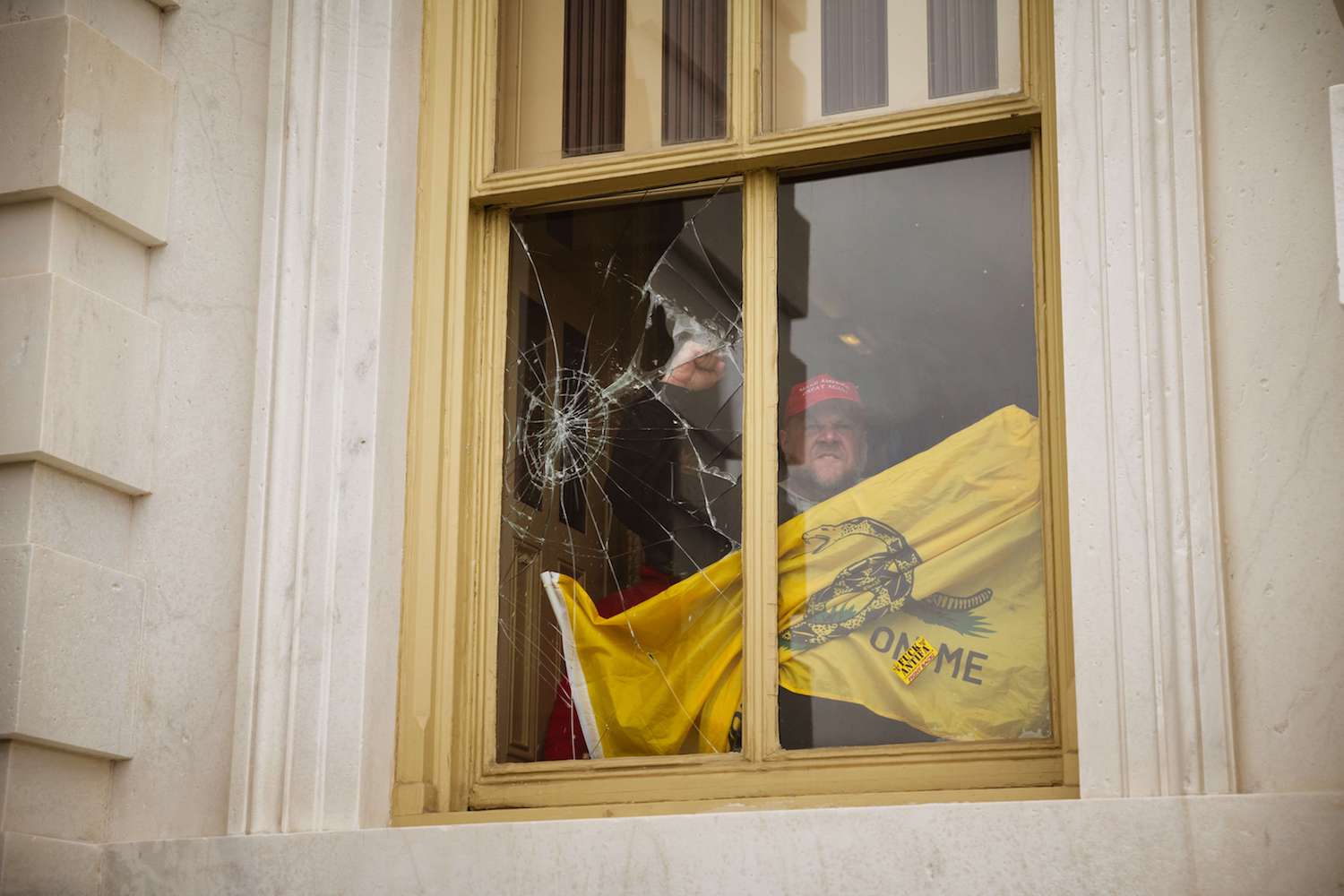 A member of a pro-Trump mob shatters a window with his fist from inside the Capitol Building after breaking into it on January 6, 2021 in Washington, DC. (AFP)