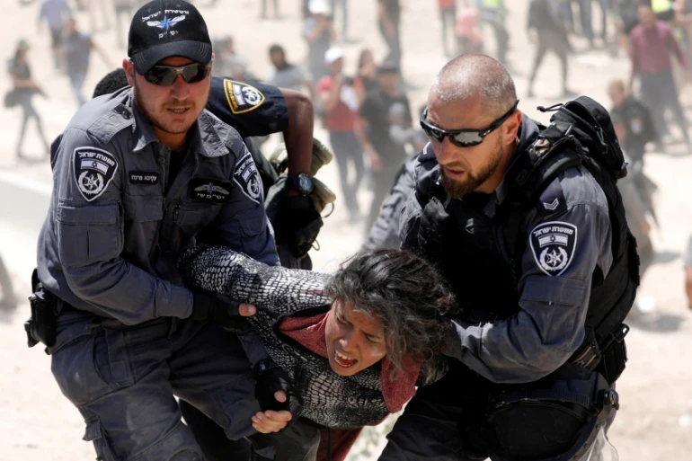 Israeli policemen detain a girl in the Palestinian Bedouin village of Khan al-Ahmar, near Jerusalem, in the occupied West Bank, July 4, 2018. (Reuters)