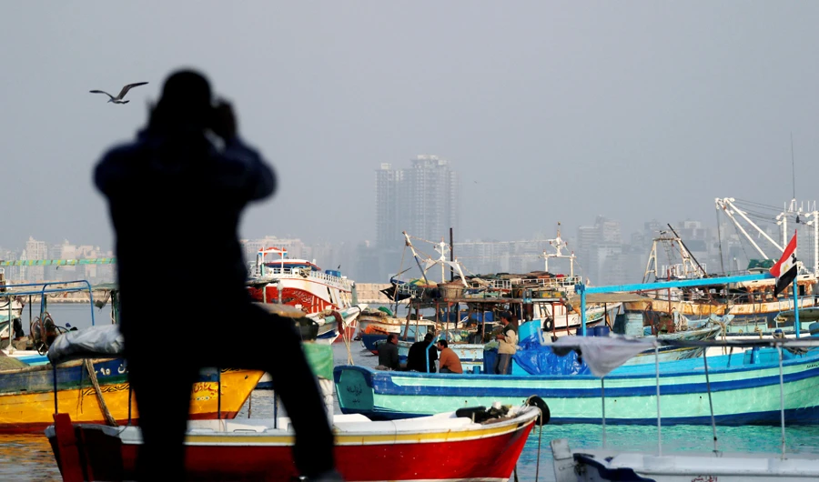 A man takes a picture of fishing boats docked along the Mediterranean Sea, north of Cairo, Egypt December 6, 2020. (REUTERS)
