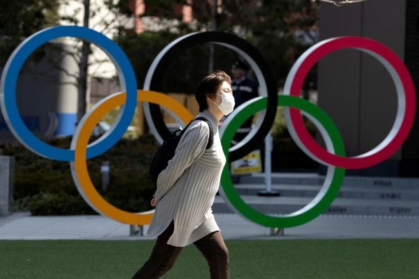 A woman wearing a protective face mask, following an outbreak of the coronavirus disease (COVID-19), walks past the Olympic rings in front of the Japan Olympics Museum in Tokyo, Japan March 13, 2020. (Reuters)