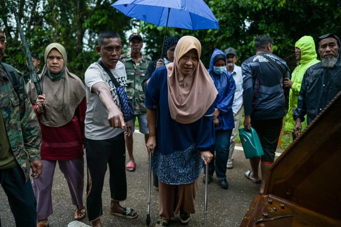 A woman walks with the help of walking aids after being evacuated from an area where the road is currently submerged under floodwaters in Sementeh, near Lanchang in Malaysia’s Pahang state on Jan. 6, 2020. (AFP)