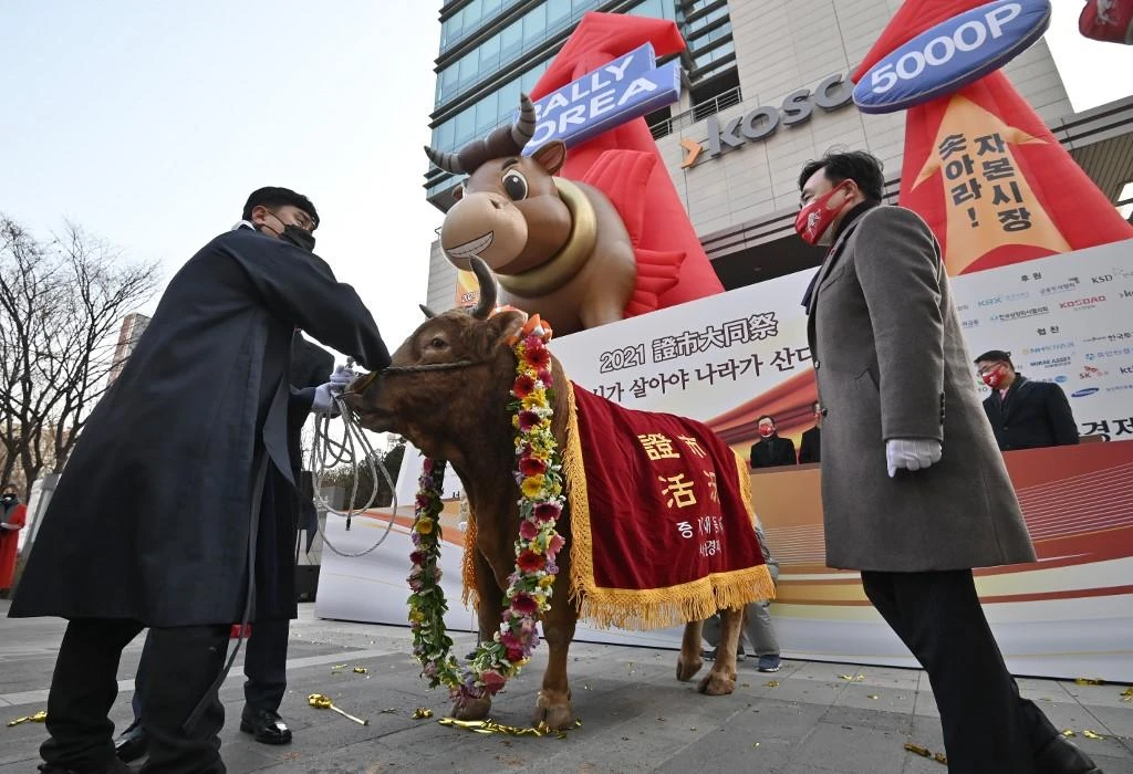 A man holds onto a bull during a ceremony marking the opening of the stock market at the Korea Exchange in Seoul on Jan. 4, 2021, on the first trading day of the new year. (AFP)