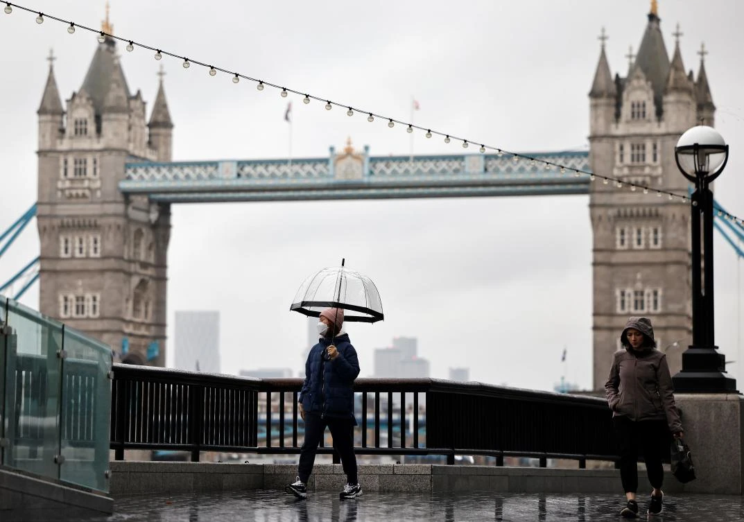Pedestrians walk along the embankment, near Tower Bridge, as Britain enters a national lockdown in London on January 5, 2021. (AFP)