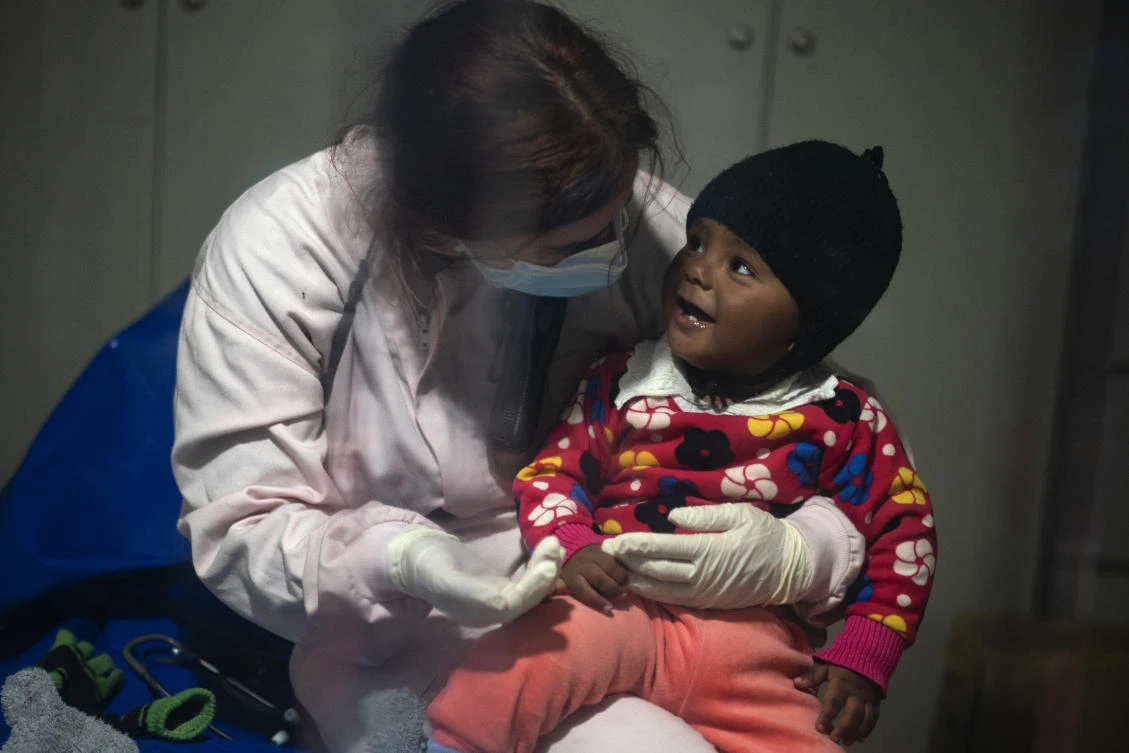 Dr. Bego Motriko, with the Spanish NGO Open Arms, sits with a baby after being rescued on an overcrowded wooden boat in the Mediterranean sea on Saturday, Jan. 2, 2021, aboard the NOG’s vessel. (AP)