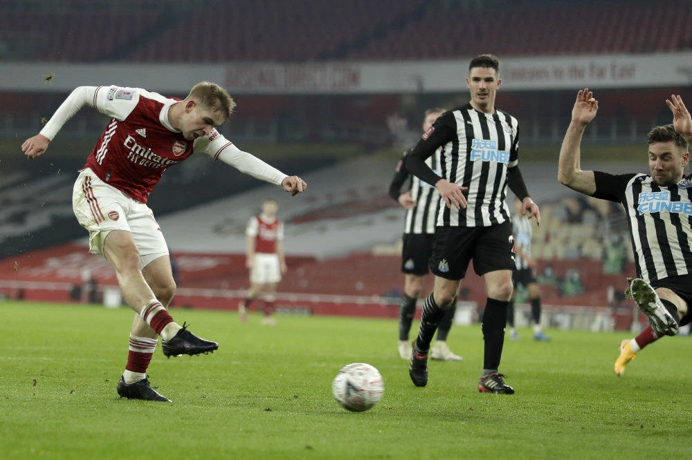 Arsenal's Emile Smith Rowe, left, scores the opening goal during the English FA Cup third round soccer match between Arsenal and Newcastle United at the Emirates Stadium in London on Jan. 9, 2020. (AP Photo/Matt Dunham)