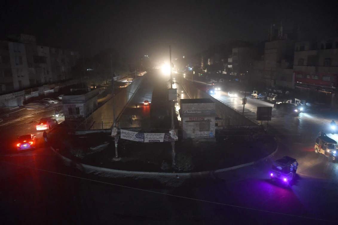 Motorists drive through a residential area during a power blackout in Pakistan's port city of Karachi early on January 10, 2021. (AFP)