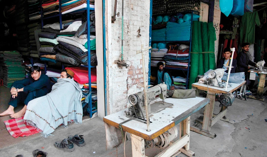 Tailors sit at their shops in Peshawar on Sunday as the country is hit by nationwide power blackout. Power was restored later in the day. (AFP)