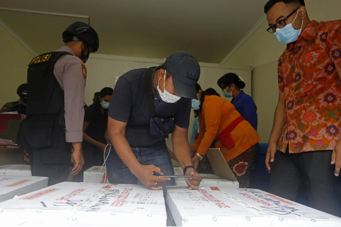 Health workers check the boxes containing coronavirus vaccines developed by China’s Sinovac Biotech as they arrived in Bali, Indonesia on Thursday, Jan. 7, 2021. (AP)