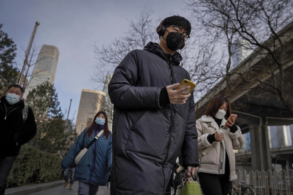 A man wearing a face mask and a disposable gloves to help curb the spread of the coronavirus heads to work with other masked people during the morning rush hour in Beijing. (File/AP)