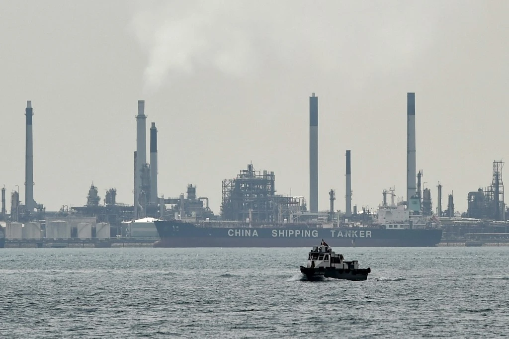 A boat (foreground) is seen past an oil tanker (background) docked next to an oil refinery on Bukom island off Singapore on Jan. 18, 2016. (File/AFP)
