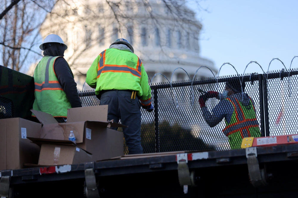 Workers install razor wire atop the unscalable fence surrounding the US Capitol in the wake of the January 6th riot and ahead of the upcoming inauguration in Washington on January 14, 2021. (REUTERS/Jonathan Ernst)