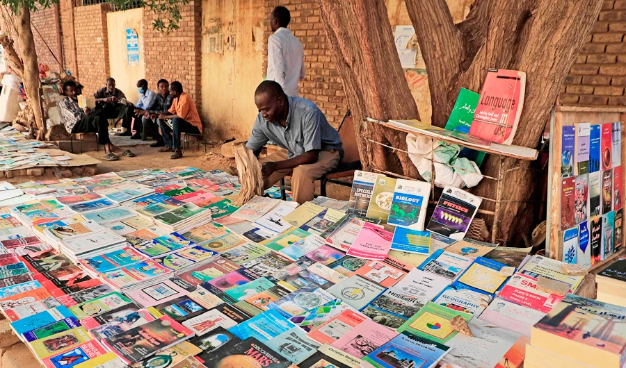 Bookseller Yaqoub Mohamed Yaqoub, 45, sits by his roadside stall where he has been working for 15 years, in the Sudanese capital Khartoum, on January 14, 2021. (AFP)