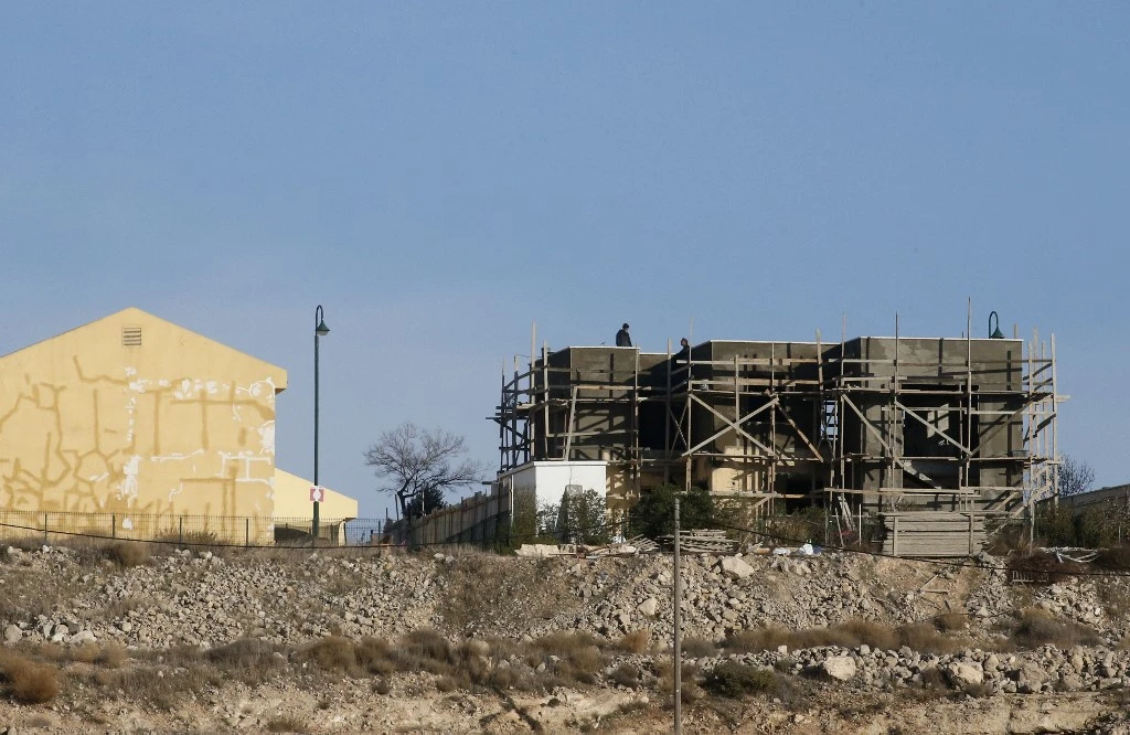 Laborers work on the roof of a building under construction in the Israeli settlement of Karmel in the southern area of Hebron city in the occupied West Bank, on Jan. 12, 2021. (AFP)