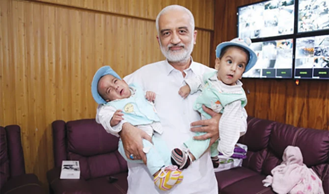 Sarim Burney holds the previously conjoined Pakistani twins, Muhammad Ayan and Muhammad Aman, in this undated photo. (Supplied)