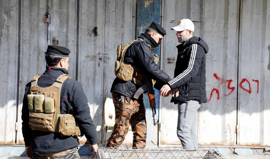 An Iraqi security force member checks a man near the damage site in the aftermath of a twin suicide bombing attack in a central market, in Baghdad, Iraq January 22, 2021. (REUTERS)