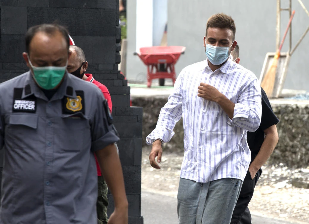 Russian citizen Sergei Kosenko, right, is escorted by an Indonesian immigration officer at Immigration office in Nusa Dua, Bali, Indonesia on Sunday, Jan. 24, 2021. (AP)