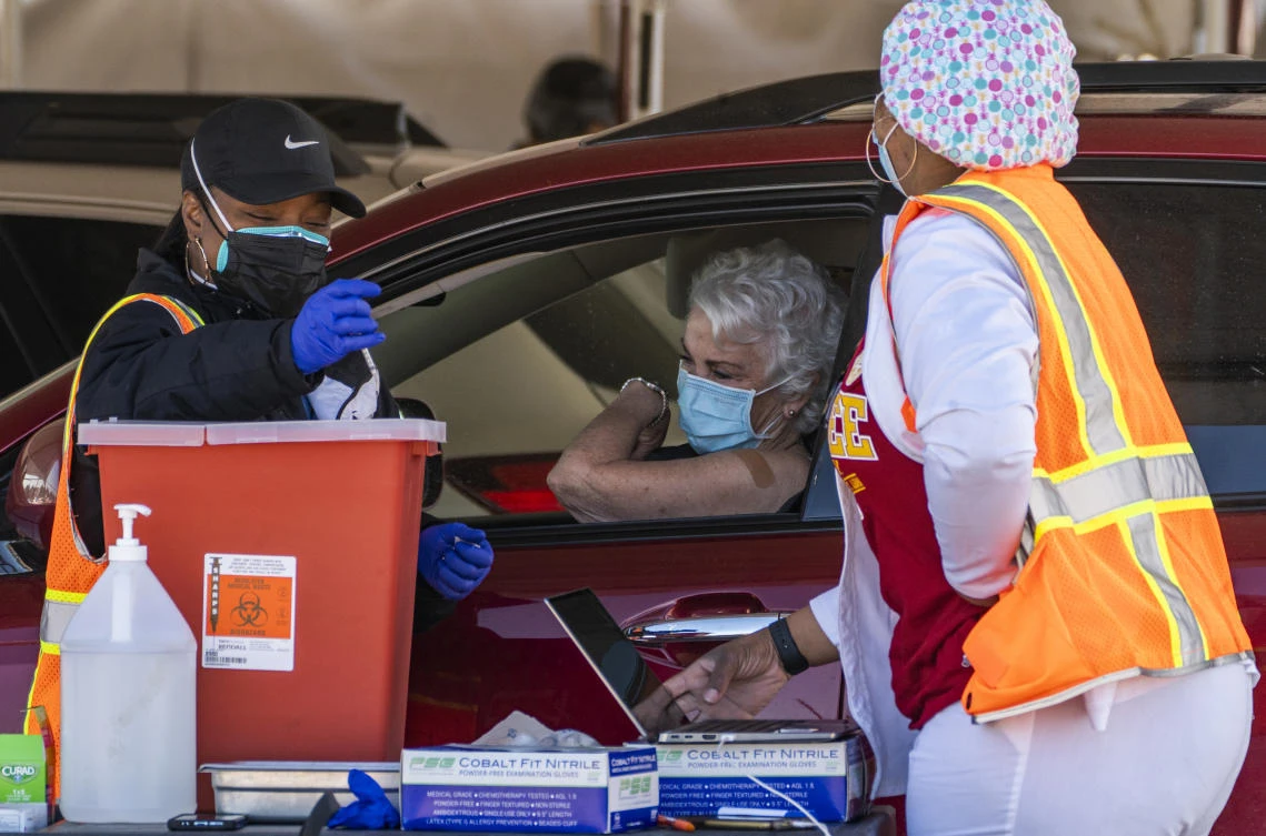 In this Jan. 26, 2021, file photo, a woman is vaccinated inside her vehicle at a mass COVID-19 vaccination site outside The Forum in Inglewood, Calif. (AP, File)