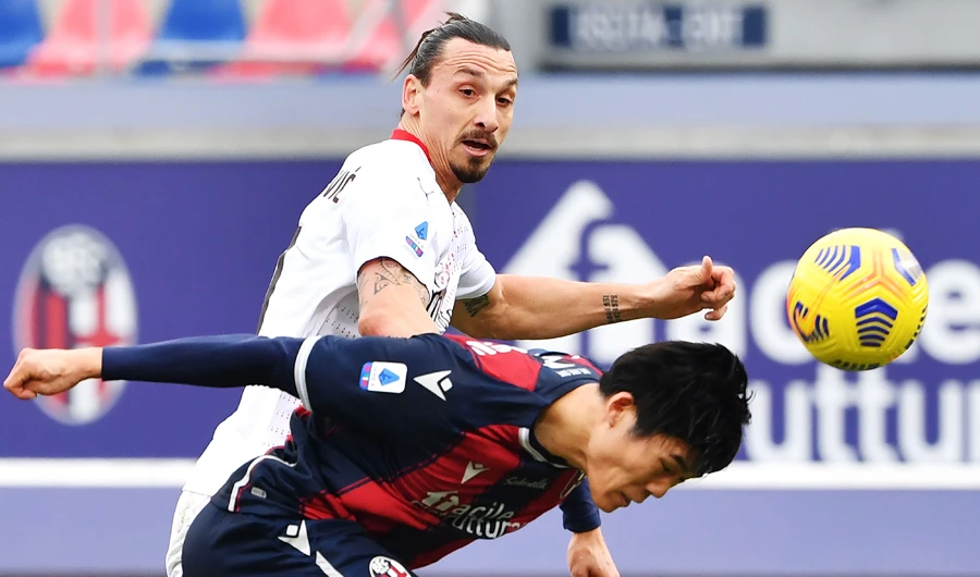 Bologna's Japanese defender Takehiro Tomiyasu (R) heads the ball past AC Milan's Swedish forward Zlatan Ibrahimovic during the Serie A football match between Bologna and AC Milan on January 30, 2021 at the Dall'Ara stadium in Bologna. (AFP)