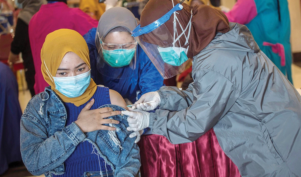 A health worker, right administers COVID-19 vaccine in Surabaya. (AFP)