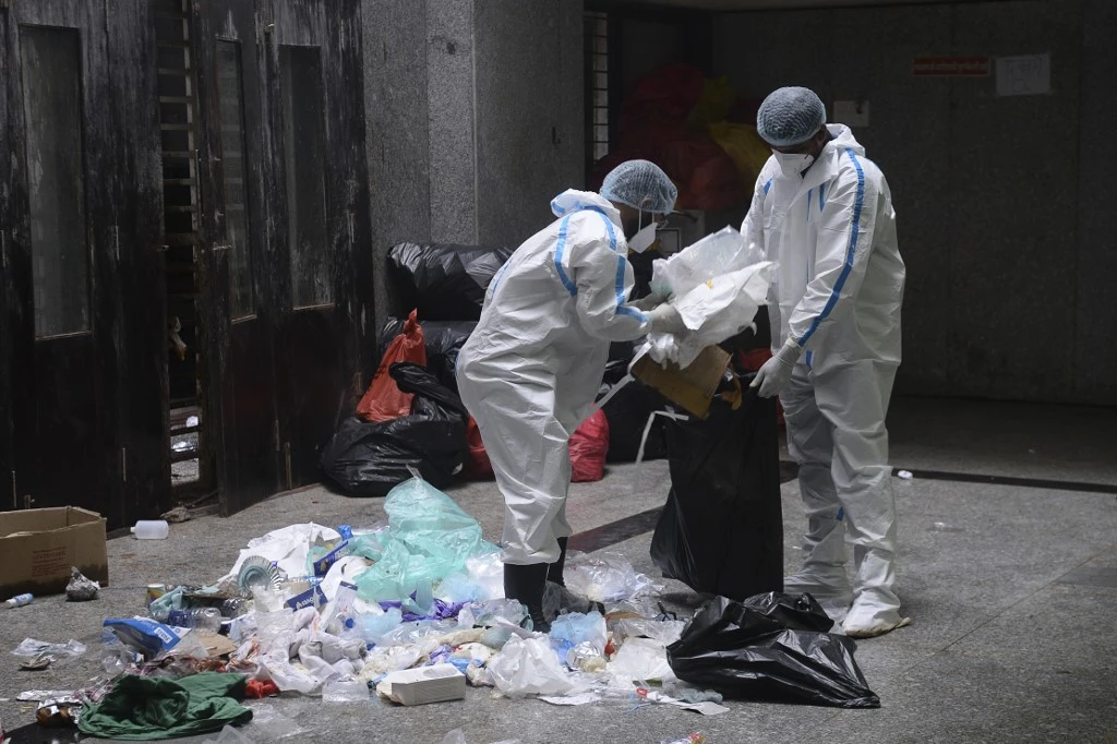 Medical staff wearing PPE collect medical waste during a COVID-19 screening at a coronavirus facility in India. (File/AFP)
