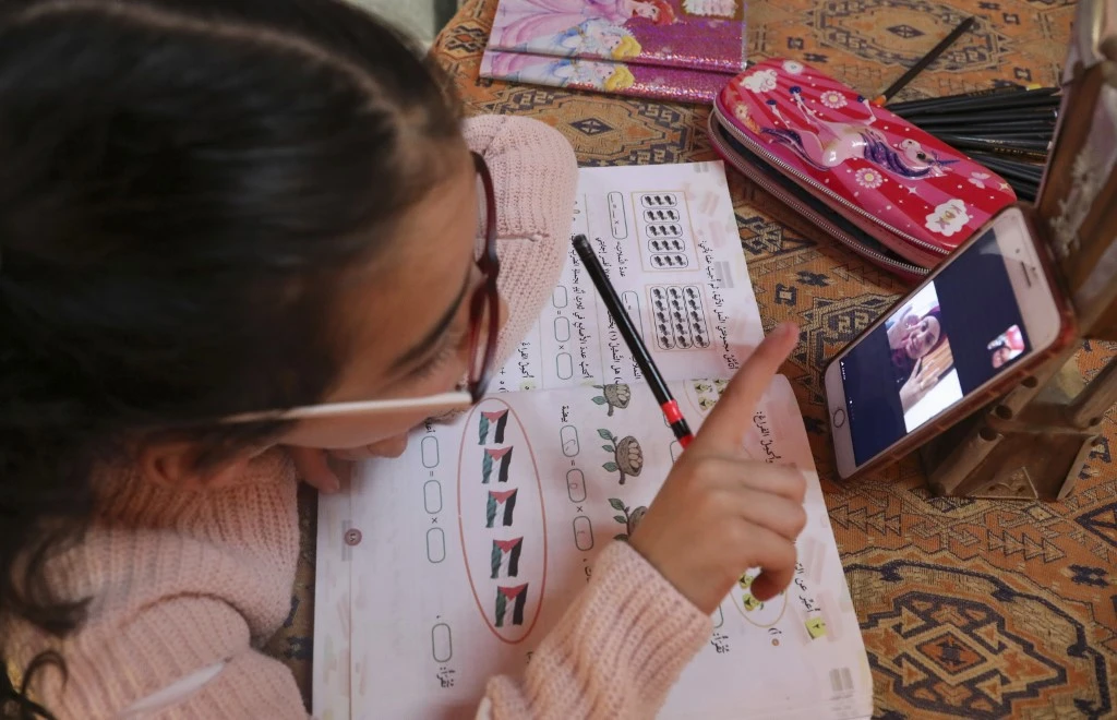 Zeina Amro attends an online class at home due to the coronavirus in the West Bank village of Dura near Hebron. (File/AFP)