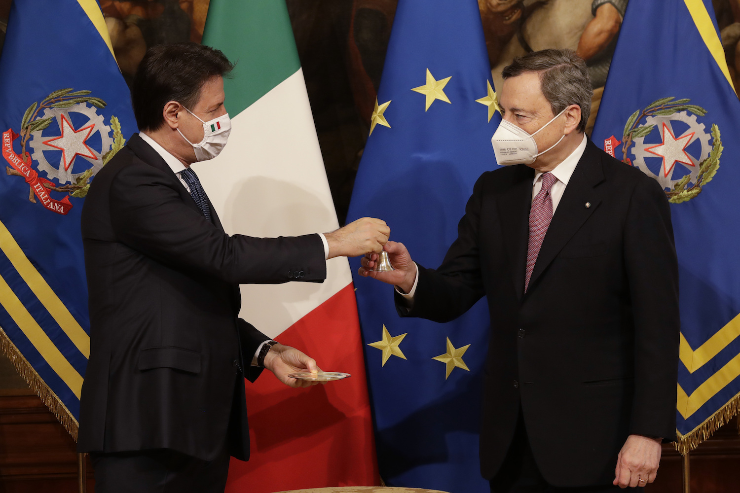Italian outgoing Premier Giuseppe Conte hands over the cabinet minister bell to new Premier Mario Draghi, during the handover ceremony at Chigi Palace Premier's office, in Rome, Saturday, Feb. 13, 2021. (AP)