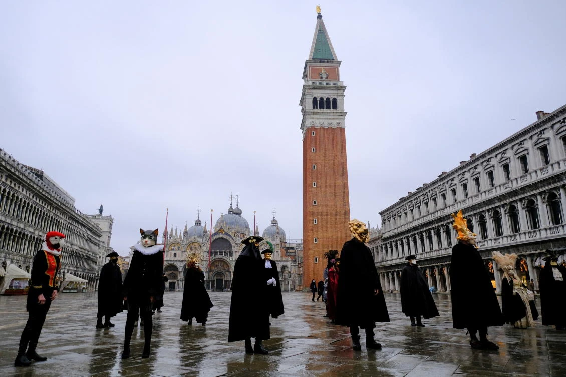 People wear carnival masks and costumes in St. Mark's Square to celebrate Venice's annual colourful carnival, which has been cancelled this year due to the coronavirus disease (COVID-19) pandemic, in Venice, Italy, February 7, 2021. REUTERS/Manuel Silvestri
