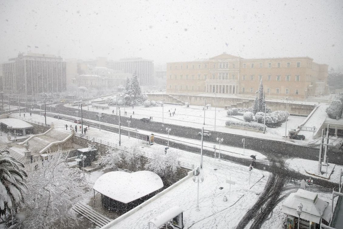 People make their way on Syntagma square with the parliament building seen in the background, during heavy snowfall in Athens, Greece, February 16, 2021. REUTERS/Alkis Konstantinidis