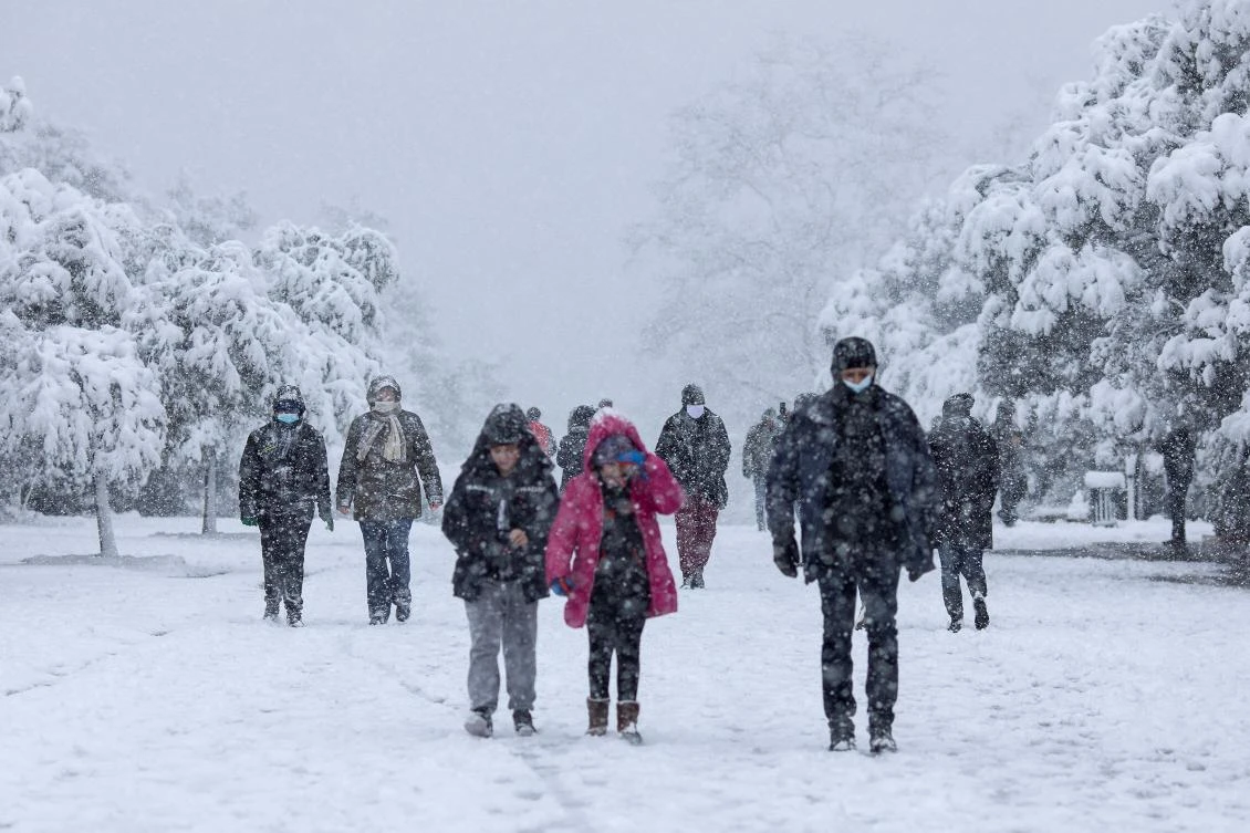 People make their way on the snow-covered Areopagitou pedestrian street under the Acropolis hill archaeological site during heavy snowfall in Athens, Greece, February 16, 2021. REUTERS/Alkis Konstantinidis