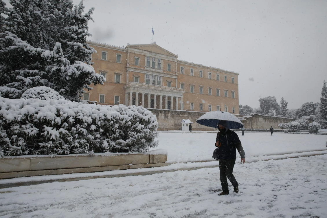 A man walks with un umbrella in front of the parliament building amid heavy snowfall in Athens, Greece, February 16, 2021. REUTERS/Costas Baltas
