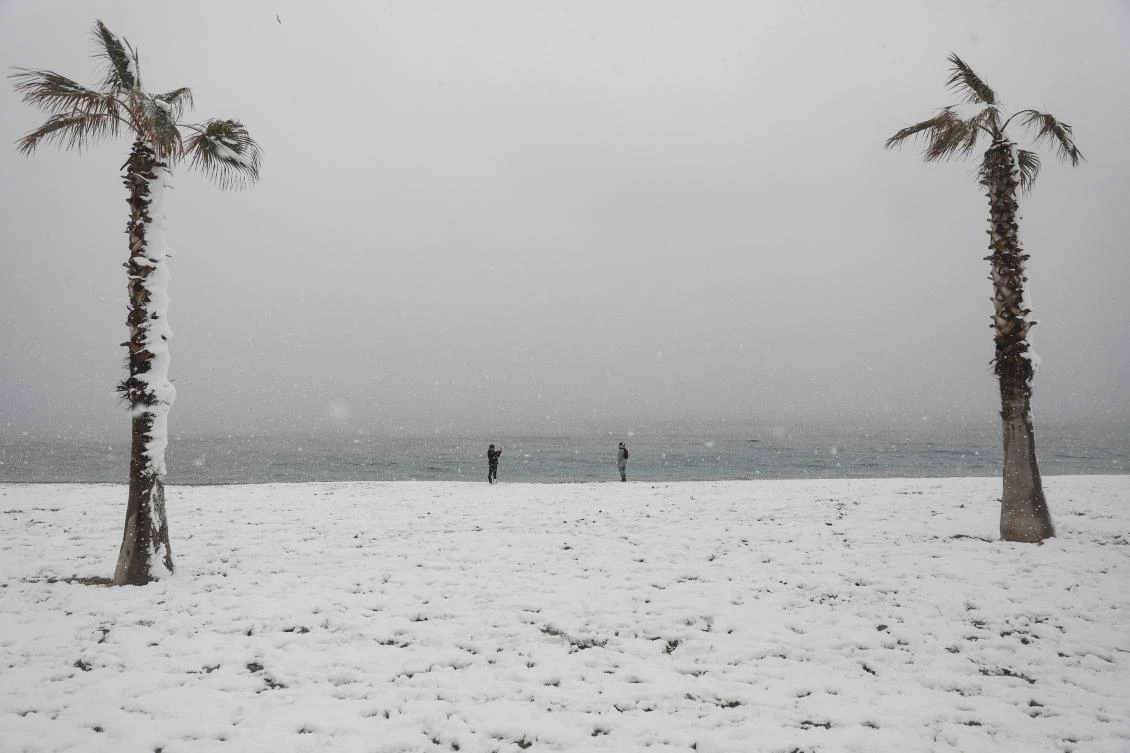 People take photos on a snow-covered beach during heavy snowfall in the suburb of Glyfada, in Athens, Greece, February 16, 2021. REUTERS/Stelios Misinas