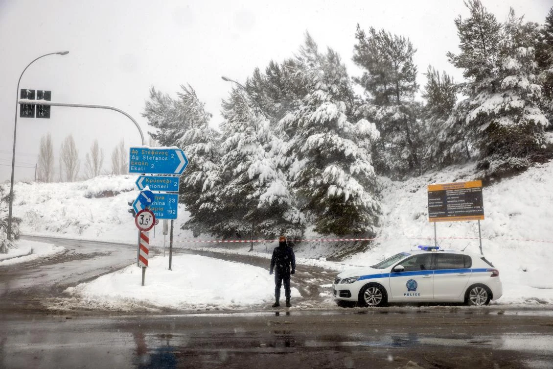 A police officer stands guard at an exit point to the national highway, which is closed due to heavy snowfall, near the village of Krioneri, Greece, February 15, 2021. REUTERS/Alkis Konstantinidis