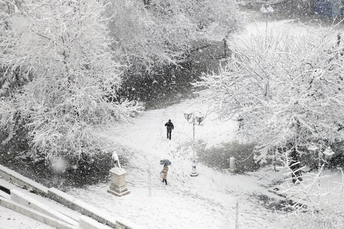 People make their way on Syntagma square during heavy snowfall in Athens, Greece, February 16, 2021. REUTERS/Alkis Konstantinidis