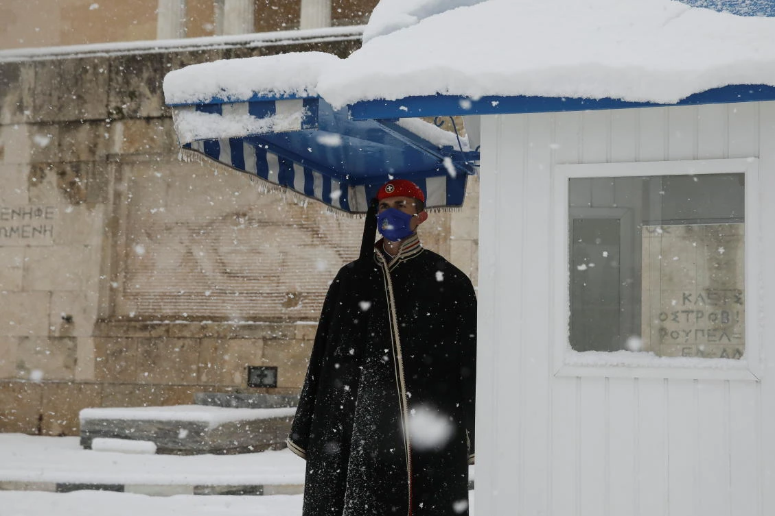 A Greek Presidential Guard wearing a protective face mask stands guard in front of the Tomb of the Unknown Soldier during heavy snowfall in Athens, Greece, February 16, 2021. REUTERS/Costas Baltas