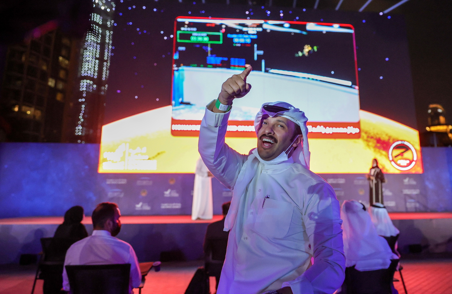 A man gestures as people watch a screen displaying information of the Hope Probe entering the orbit of Mars, in Dubai, UAE. (File/Reuters)