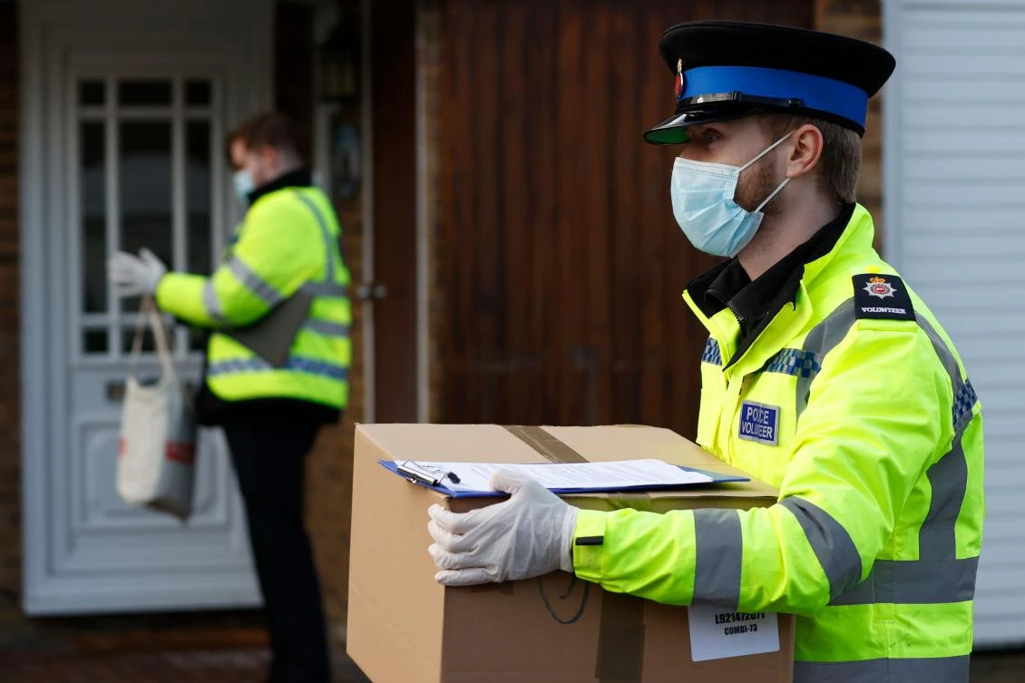 Police volunteers distribute coronavirus testing kits in the Goldsworth Park and St John's suburbs of Woking in Surrey, southwest of London, on February 2, 2021 as testing for the South African variant of Covid-19 is increased. (AFP)