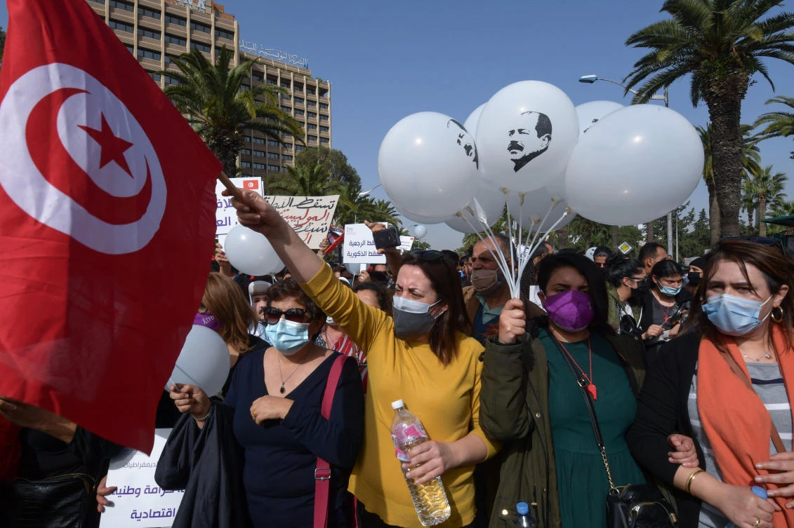 Tunisians lift placards as they demonstrate against the government and police repression in the capital Tunis on February 6, 2021, at a rally in commemoration of the 8th anniversary of the assassination of prominent leftist opposition leader Chokri Belaid. (AFP)