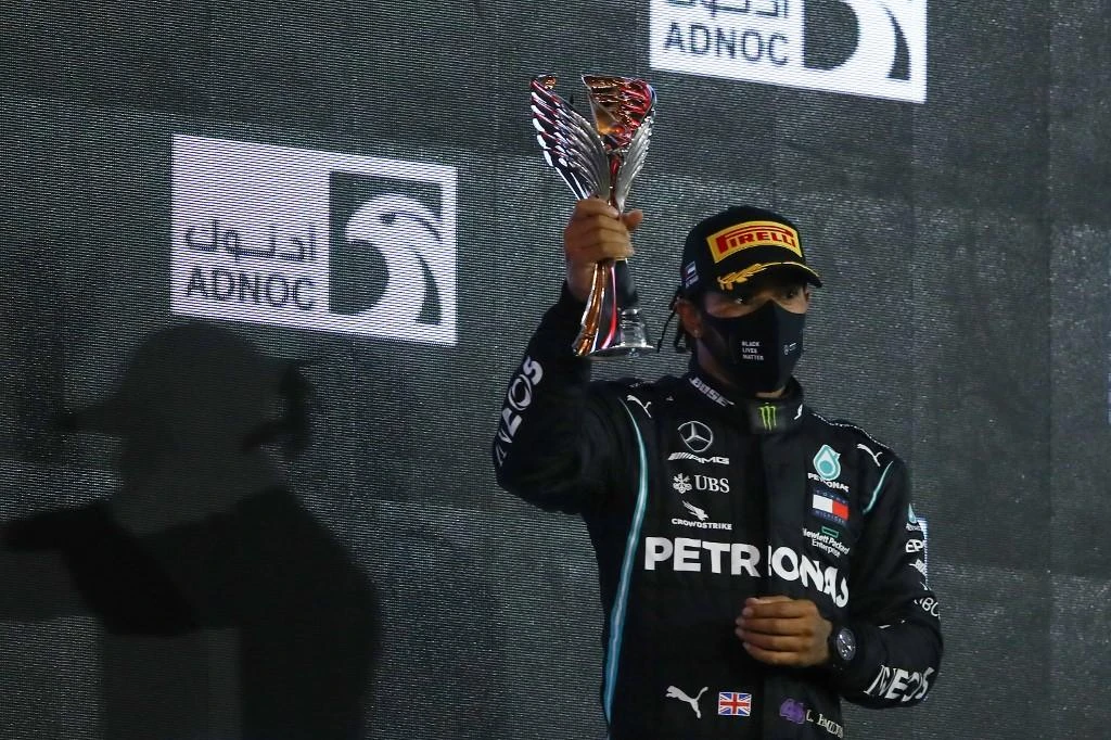 Mercedes’ driver Lewis Hamilton raises his third place trophy on the podium after the Abu Dhabi Formula One Grand Prix at the Yas Marina Circuit in Abu Dhabi on Dec. 13, 2020. (AFP)