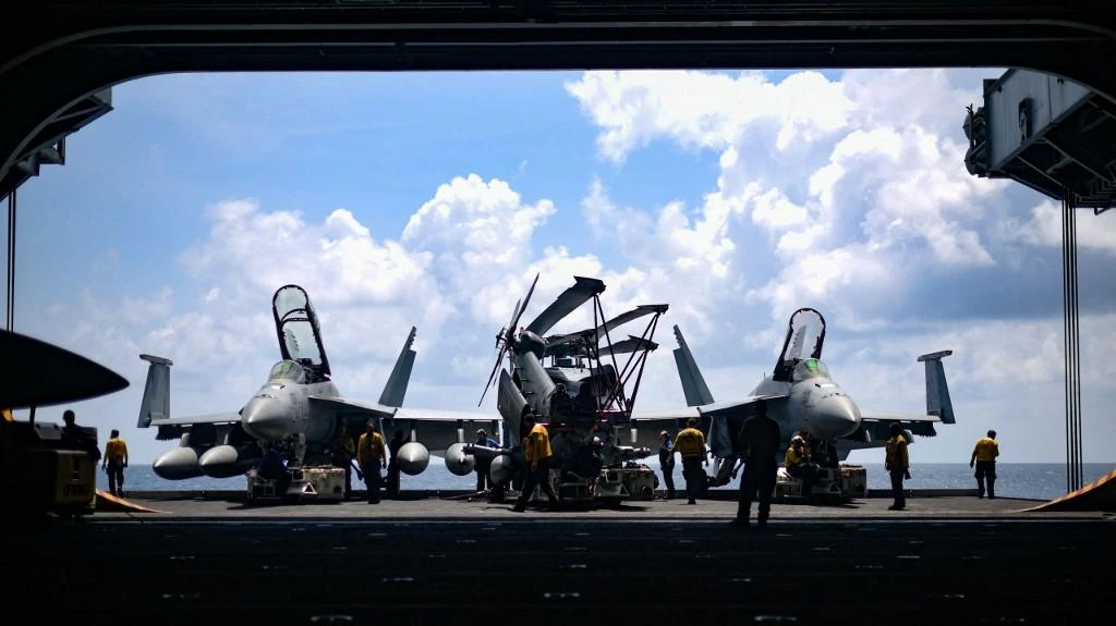 Sailors move aircraft from an elevator into the hangar bay of the aircraft carrier USS Theodore Roosevelt during an exercise on April 8, 2018 in the South China Sea. (Navy Office of Information via AFP)