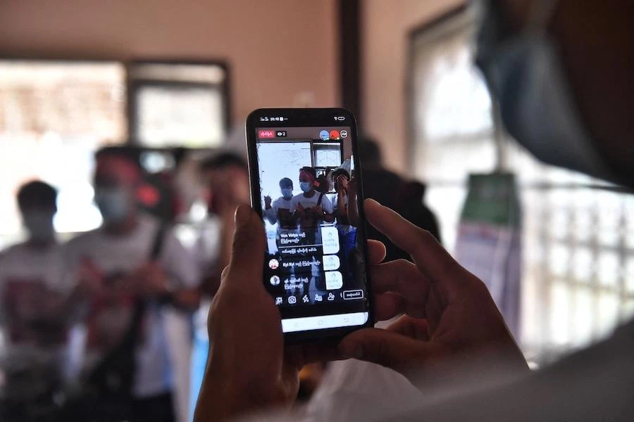 Myanmar migrants sharing their activities on social media before going to a local protest against the military coup in their home country, at a house in the outskirts of Bangkok (AFP)
