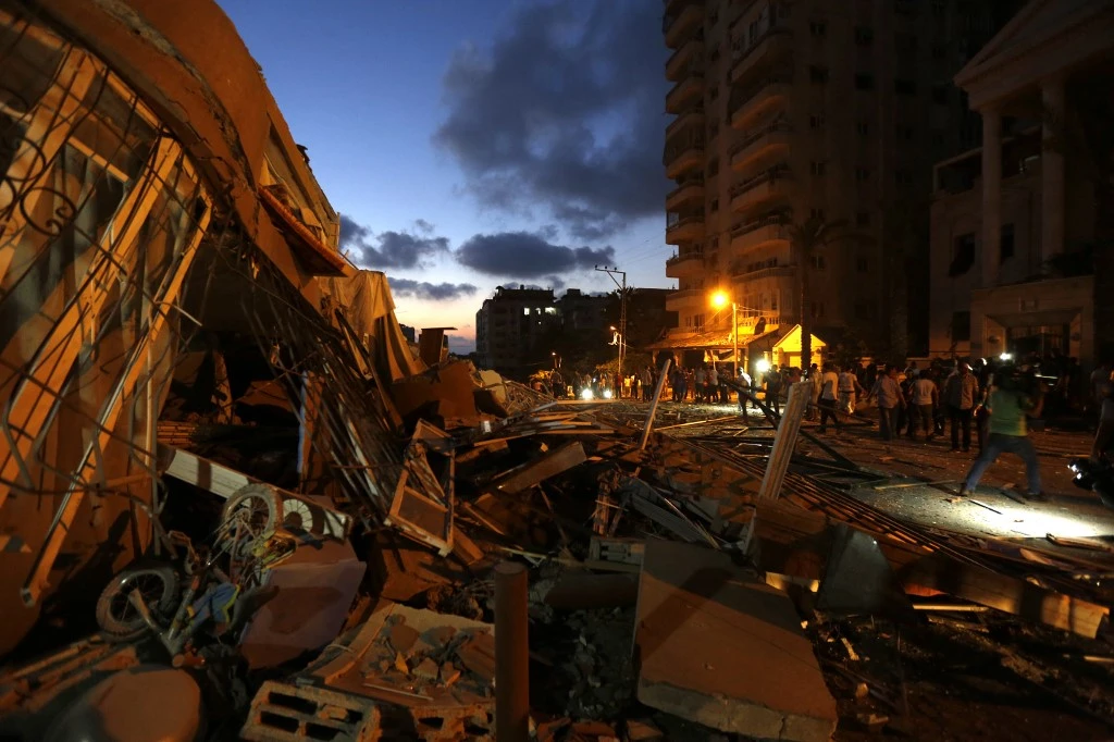 Palestinians walk next to a building that was destroyed by an Israeli air strike in Gaza City on Aug. 23, 2014. (File/AFP)
